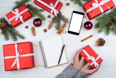 Noel hediye ambalaj arka plan, kopya alanı. Kırmızı manikür eller kırmızı kutusunda beyaz şerit yay, üstten görünüm ile tutan kadınla. Kış tatil kavramı, düz yatıyordu. Boş defter
