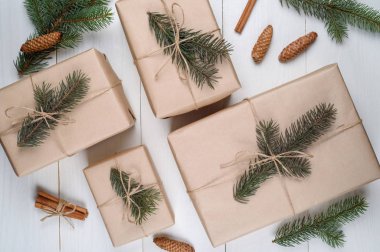 Noel arka plan hediye kutuları ile kraft kağıt köknar ağaç dalları ve beyaz ahşap arka planda, boş alan koni ile sarılı. Tatil tebrik kartı, kopya alanı. Düz yatıyordu, en iyi görünümü 