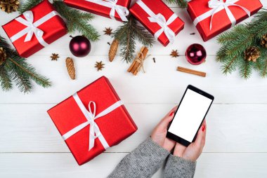Eller Mobil cep telefonu ile boş tutan kadın app tanıtımı için dokunmatik ekran, alan Kopyala. Noel süsleri. Düz yatıyordu, en iyi görünüm. Uygulama şablonu sahte 