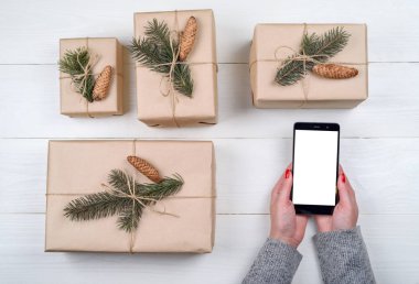 Mobil akıllı telefon ile Noel süsleri, kopya alanı ile kadın el sunuda app için boş perde. Ahşap arka plan üzerinde Noel hediyeleri. Düz yatıyordu, en iyi görünüm. Noel uygulama şablonu sahte 