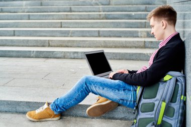 Öğrenci açık havada Üniversitesi Kampüs merdivenlerde oturan ve laptop ile çalışma, sınavlara hazırlık, yazarak, internet'te sörf, dinlenme, kopya alanı sırt çantası ile. Teknoloji, eğitim kavramı