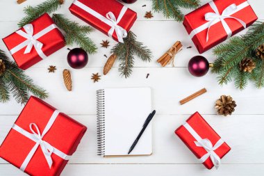 Boş defter yeni yıl gol için (veya yapılacaklar listesi), kırmızı hediye kutuları, köknar ağacı dalları, koni ve baubles beyaz masa, kopya alanı. Noel arka plan. Üstten görünüm, düz yatıyordu 