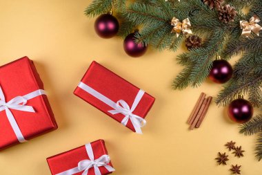 Noel arka plan kırmızı hediye kutuları, köknar ağacı dalları ile cam topları, çam kozalakları, tarçın ve Yıldız anason altın arka plan üzerinde boş alan. Kopya alanı düz yatıyordu, en iyi manzaralı 