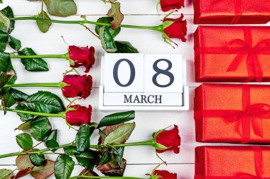 Kırmızı hediye kutuları, güller ve beyaz ahşap arka planda, küp takvim metin için yer kopyalayın. Tarihi beyaz blok takvim 8 Mart kadın günler için sakla. Tebrik kartı. Üstten görünüm, düz yatıyordu
