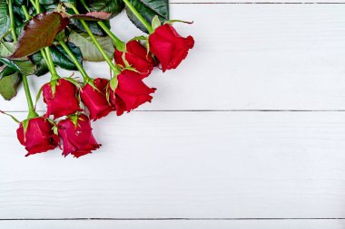 Tatil arka plan ile ahşap masa, kopya alanı için metin üzerinde kırmızı gül buketi. Düz yatıyordu, en iyi görünüm. Kadının gün (8 Mart), Sevgililer günü, anneler günü için tebrik kartı