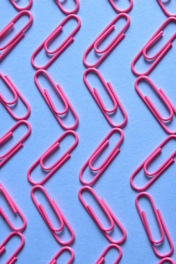 Pastel pembe kağıt kliplerinde mavi arka plan, kopya alanı. Üstten görünüm, düz yatıyordu. Okul, Kolej, eğitim kavramı hazırlıkları. Dalga ataç yaptı. Arka plan