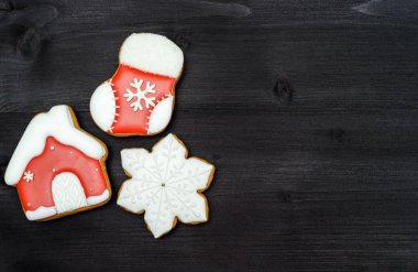 Üstten görünüm, koyu ahşap masa üzerine krema ile lezzetli ev yapımı gingerbread çerezleri lay düz. Kar tanesi, çorap ve evi, kopya alanı ile Noel arka plan. Tatil Gıda