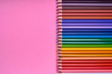 Kalemler üzerinde pastel pembe renk, yakın çekim. Renkli kalemler ayarla, alanı Kopyala. Boya kalemi. Üstten görünüm, düz yatıyordu. Okul hazırlıkları kavramı kolej. Arka plan