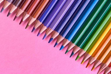 Kalemler üzerinde pastel pembe renk, yakın çekim. Renkli kalemler ayarla, alanı Kopyala. Boya kalemi. Üstten görünüm, düz yatıyordu. Okul hazırlıkları kavramı kolej. Arka plan