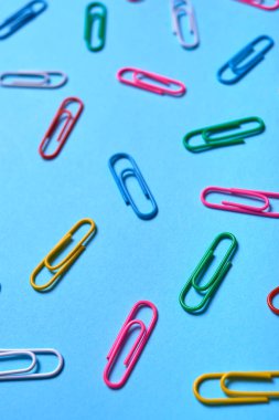 Mavi arka plan, kopya alanı üzerinde renkli ataç. Üstten görünüm, düz yatıyordu. Okul, Kolej, eğitim kavramı hazırlıkları. Beyaz, pembe, mavi, kırmızı, sarı, yeşil ataç. Arka plan