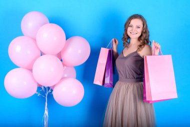 Alışveriş torbaları pembe balonlar yakınındaki mavi arka plan üzerinde siyah Cuma tatil, boş alan tutan güzel genç gülümseyen kadın. Güzellik, moda, satış konsepti. Mavi arka plan kopya alanı ile kız