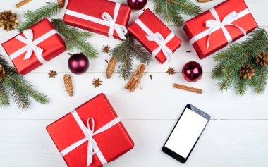 Noel kırmızı hediye kutuları, köknar ağacı dalları, koniler, baubles ve mobil akıllı telefon ile beyaz boş perde app sunum, kopya alanı için arka plan. Üstten görünüm, düz yatıyordu 