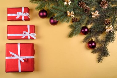 Noel arka plan kırmızı hediye kutuları, köknar ağacı dalları ile cam topları, çam kozalakları, tarçın ve Yıldız anason altın arka plan üzerinde boş alan. Kırmızı lüks yeni yıl hediye, kopya alanı