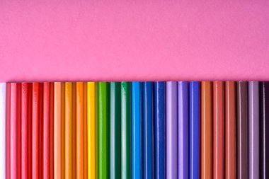 Kalemler üzerinde pastel pembe renk, yakın çekim. Renkli kalemler ayarla, alanı Kopyala. Boya kalemi. Üstten görünüm, düz yatıyordu. Okul hazırlıkları kavramı kolej. Arka plan