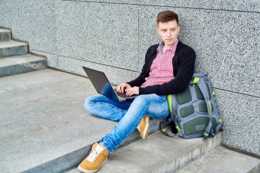 Öğrenci açık havada Üniversitesi Kampüs merdivenlerde oturan ve laptop ile çalışma, sınavlara hazırlık, yazarak, internet'te sörf, dinlenme, kopya alanı sırt çantası ile. Teknoloji, eğitim kavramı