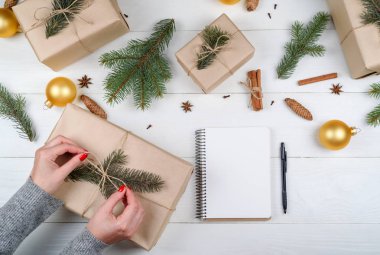 Arka plan boş defter, kopya alanı ile kaydırma Noel hediyesi. Noel hediyesi kutu tutan eller kraft, üstten görünüm tamamladı. Kış tatil kavramı, düz yatıyordu. Kadın ambalaj Hediyelik