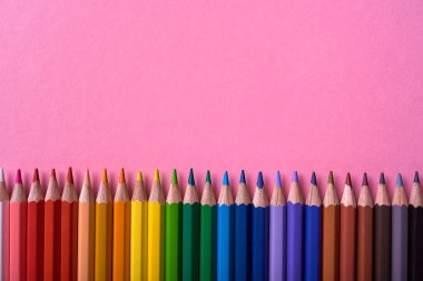 Kalemler üzerinde pastel pembe renk, yakın çekim. Renkli kalemler ayarla, alanı Kopyala. Boya kalemi. Üstten görünüm, düz yatıyordu. Okul hazırlıkları kavramı kolej. Arka plan