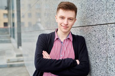 Portre yakışıklı erkek öğrenci ile ayakta eller gri taş duvar ve dinlenme Üniversitesi Kampüs mekanlarda, kopya alanı olan haçlar. Eğitim, dinlenmek ve rahatlamak, seyahat ve Turizm kavramı 