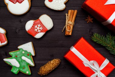 Noel gingerbread çerezleri, kırmızı hediye kutuları, köknar ağacı dalı, koni ve koyu ahşap zemin, üzerine tarçın alanı kopyalayın. Üstten görünüm, düz yatıyordu. Çam ağacı, kardan adam, çorap. Tatil kavramı