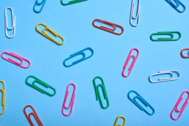 Mavi arka plan, kopya alanı üzerinde renkli ataç. Üstten görünüm, düz yatıyordu. Okul, Kolej, eğitim kavramı hazırlıkları. Beyaz, pembe, mavi, kırmızı, sarı, yeşil ataç. Arka plan