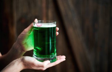 Kadın holding kupa ahşap arka plan üzerinde dudak baskı ile yeşil bira alanı kopyalayın. Bardak bira barda tutan el. St Patricks Günü, 17 Mart için tebrik kartı