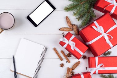 Noel arka plan kırmızı hediye kutuları, cep telefonu ile beyaz perde ve boş defter, kopya alanı ile. Yeni yıl amaç ya da kararlar için şablon