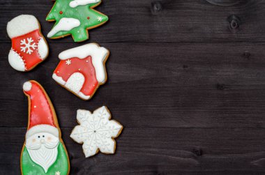 Üstten görünüm, koyu ahşap masa üzerine krema ile lezzetli ev yapımı gingerbread çerezleri lay düz. Noel, Noel Baba, kar tanesi, çorap, köknar ağacı ve ev, kopya alanı boder ile arka plan. Tatil Gıda
