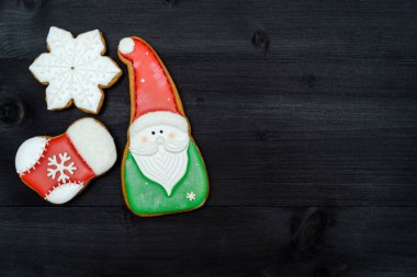 Üstten görünüm, koyu ahşap masa üzerine krema ile lezzetli ev yapımı gingerbread çerezleri lay düz. Noel Noel Baba, kar tanesi, çorap, kopya alanı ile arka plan. Tatil Gıda