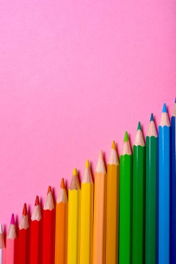Kalemler üzerinde pastel pembe renk, yakın çekim. Renkli kalemler ayarla, alanı Kopyala. Boya kalemi. Üstten görünüm, düz yatıyordu. Okul hazırlıkları kavramı kolej. Arka plan
