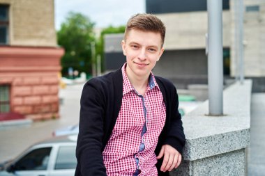 Ayakta ve geri kalan üniversite kampüsünde açık havada, kopya alanı olan gülümseyen erkek öğrenci portresi. Eğitim, dinlenmek ve rahatlamak, seyahat ve Turizm kavramı 