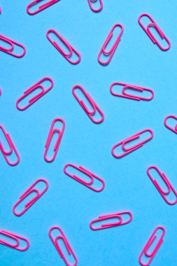 Pastel pembe kağıt kliplerinde mavi arka plan, kopya alanı. Üstten görünüm, düz yatıyordu. Okul, Kolej, eğitim kavramı hazırlıkları. Renkli ataç topluluğu. Arka plan