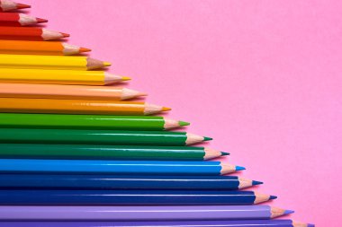 Kalemler üzerinde pastel pembe renk, yakın çekim. Renkli kalemler ayarla, alanı Kopyala. Boya kalemi. Üstten görünüm, düz yatıyordu. Okul hazırlıkları kavramı kolej. Arka plan