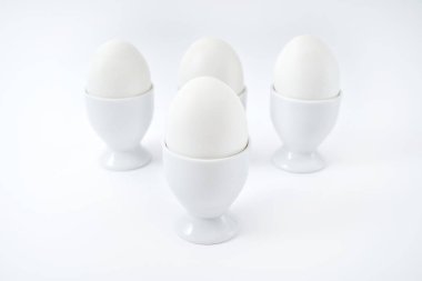 Beyaz yumurta beyaz arka plan üzerinde kopya alanı izole yumurtalık tutuyoruz. Haşlanmış yumurta standında. Sağlıklı gıda kavramı 