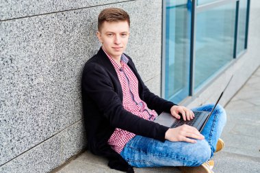 Açık havada üniversite kampüsü içinde oturan ve laptop ile çalışma, sınavlara hazırlık, yazarak, internet'te sörf, dinlenme, kopya alanı öğrenci. Teknoloji, eğitim kavramı