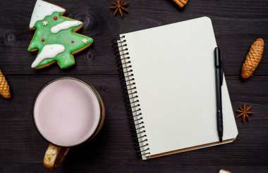 Açık boş defter ile kopya alanı için metin, fincan kakao ve köknar ağacı zencefilli kurabiye koyu ahşap masa üzerinde. Üstten görünüm, düz yatıyordu. Noel arka plan. Yeni yıl kararları, gol, boş alan
