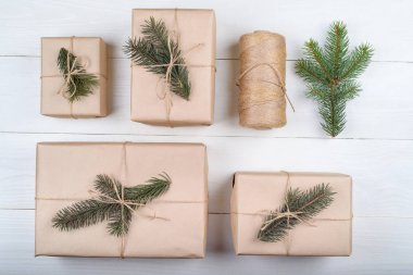 Noel hediye kutuları ile arka plan beyaz ahşap arka planda, boş alan köknar ağacı dalları ile kraft kağıt sarılı. Tatil tebrik kartı, kopya alanı. Düz yatıyordu, en iyi görünümü 