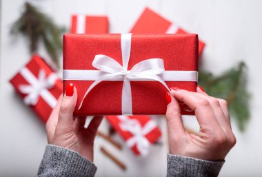 Kırmızı Noel hediyesi Beyaz ahşap arka plan üstüne tutan genç kadın el kapatın. Noel arka plan kırmızı hediye kutuları ile. Düz yatıyordu, en iyi görünümü