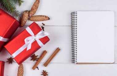 Boş günlüğü, kırmızı hediye kutuları, köknar ağacı dalları, çam kozalakları, tarçın ve anasonu Beyaz ahşap arka planda, kopya alanı ile Noel arka plan. Düz yatıyordu, en iyi görünüm. Noel planlama kavramı