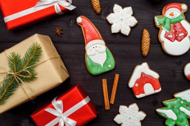 Noel gingerbread çerezleri, hediye kutuları, tarçın, koniler, köknar ağacı dalları koyu ahşap arka plan, kopya alanı üzerinde. Üstten görünüm, düz yatıyordu. Noel Baba, kar tanesi, çam ağacı, house, kardan adam. Tatil kavramı