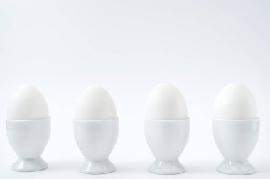 Beyaz yumurta beyaz arka plan üzerinde kopya alanı izole yumurtalık tutuyoruz. Satır standında haşlanmış yumurta. Sağlıklı gıda kavramı 