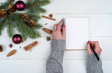 Üstten görünüm Noel arka plan boş boş günlüğü ve kızın kalemle yazma beyaz ahşap arka plan üzerinde listelemek için boş alan eller. Düz yatıyordu, en iyi görünümü