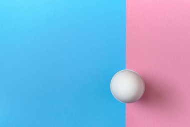 Yumurtalık mavi ve pembe pastel arka plan, kopya alanı üzerinde beyaz yumurta ayakta. Kağıt arka plan iki rengi ile kürsüye haşlanmış yumurta. Sağlıklı gıda kavramı. Paskalya yumurtası. Düz yatıyordu, en iyi görünümü