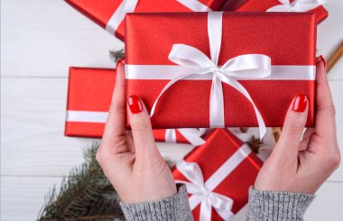 Kırmızı Noel hediyesi Beyaz ahşap arka plan üstüne tutan genç kadın el kapatın. Noel arka plan kırmızı hediye kutuları ile. Düz yatıyordu, en iyi görünümü