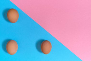Kahverengi mavi ve pembe pastel arka planda, kopya alanı yumurta. Kağıt arka plan iki rengi ile üzerinde yumurta. Sağlıklı gıda kavramı. Paskalya yumurtaları. Düz yatıyordu, en iyi görünümü
