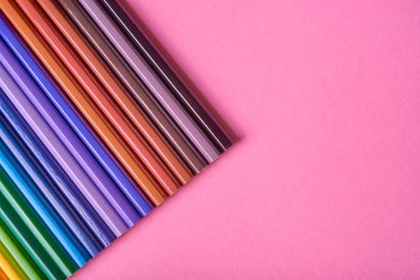 Kalemler üzerinde pastel pembe renk, yakın çekim. Renkli kalemler ayarla, alanı Kopyala. Boya kalemi. Üstten görünüm, düz yatıyordu. Okul hazırlıkları kavramı kolej. Arka plan