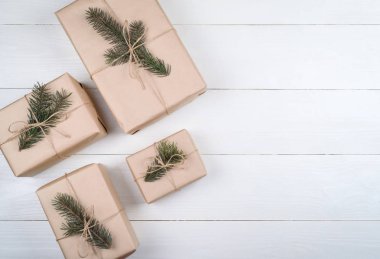 Noel hediye kutuları ile arka plan beyaz ahşap arka planda, boş alan köknar ağacı dalları ile kraft kağıt sarılı. Tatil tebrik kartı, kopya alanı. Düz yatıyordu, en iyi görünümü 