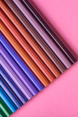 Kalemler üzerinde pastel pembe renk, yakın çekim. Renkli kalemler ayarla, alanı Kopyala. Boya kalemi. Üstten görünüm, düz yatıyordu. Okul hazırlıkları kavramı kolej. Arka plan