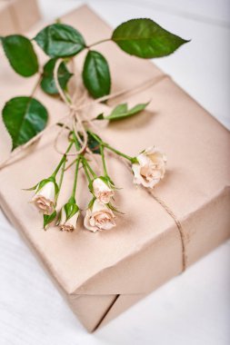 Hediye kutusu ile taze gül dalı ile ahşap masa, kopya alanı bırakır. Tatil arka plan, satış, alışveriş. Tebrik kartı için Sevgililer günü, Bayan günü, anneler günü, Doğum günü, Paskalya, düz yatıyordu