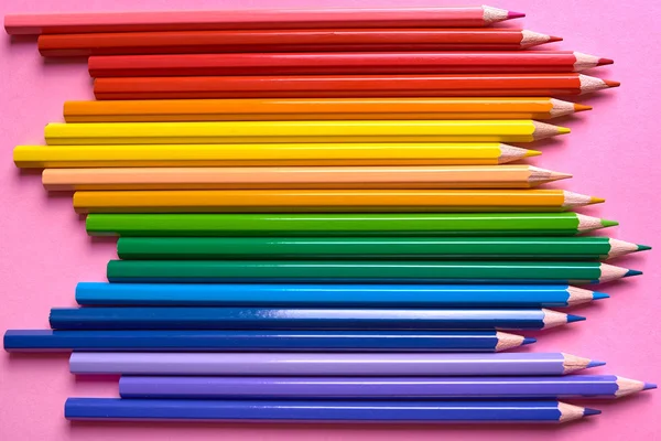 Colorful pencils of rainbow colors on pink pastel background, close up. Set of colorful pencils, copy space. Crayons. Top view, flat lay. Back to school, college concept. Abstract background