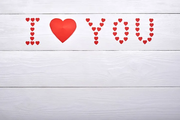 White wooden background with sign I Love You made from red paper hearts, copy space. Greeting card mockup for Valentines Day. Symbol of love. Love concept, Top view, flat lay
